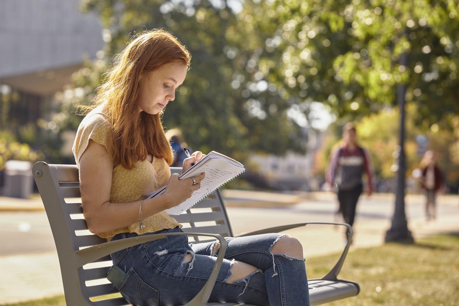 一位<a href='http://0kau3.scv98.com'>全球十大赌钱排行app</a>学院的学生在校园里的长椅上读书.